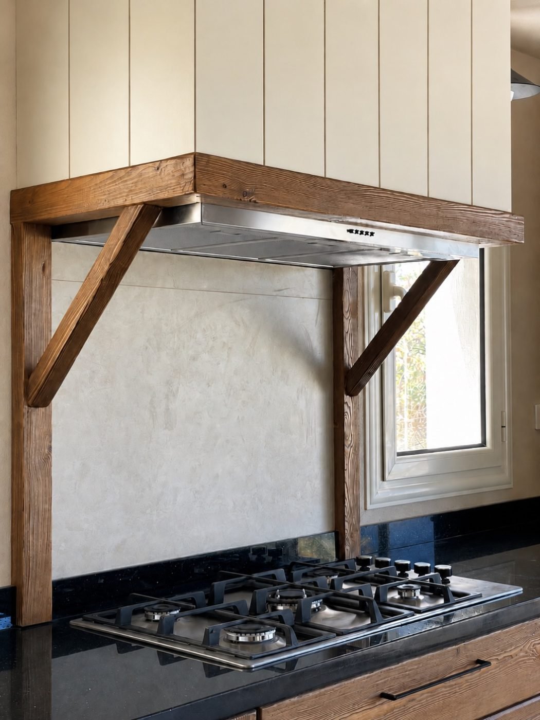Timber-framed range hood. Cream paneling, solid timber brackets, dark stone worktop