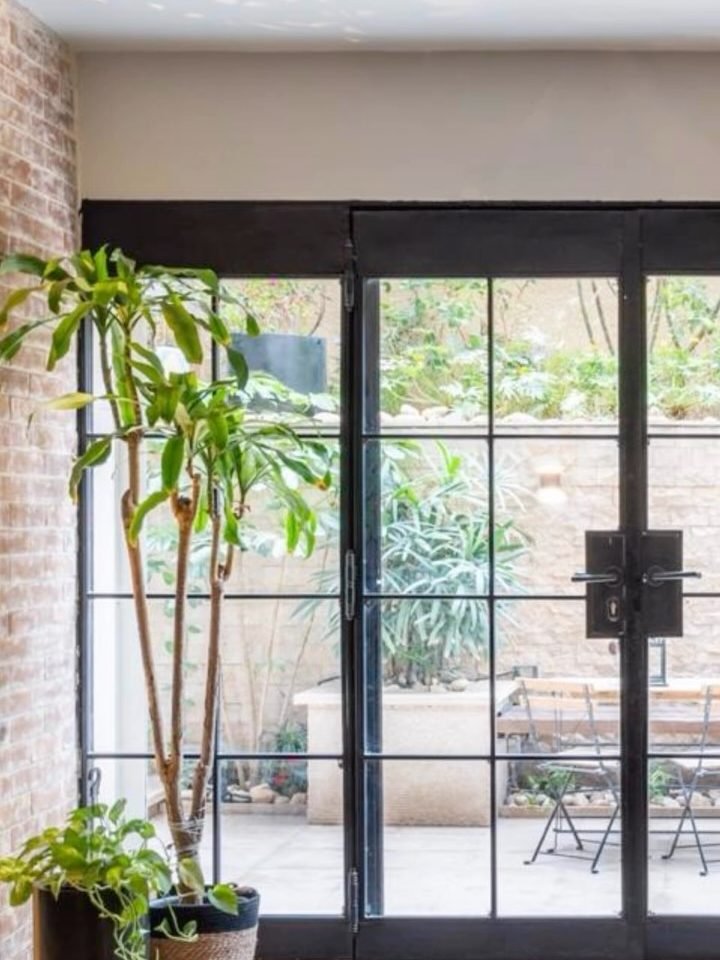 Steel-framed glass doors. An exposed-brick room opening onto the courtyard