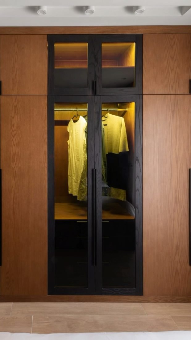 Oak wardrobe with smoked glass. Lit hanging bays behind black-framed doors